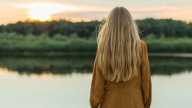 Woman looking over a river into the sunset