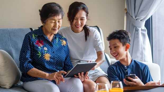 Multi generation family using digital tablet on sofa