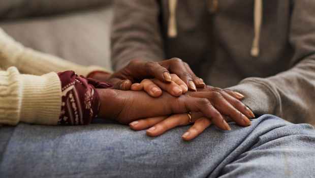 Close-up photo of hands held over one another in a comforting way