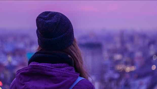 hipster girl looking out into the city at dusk
