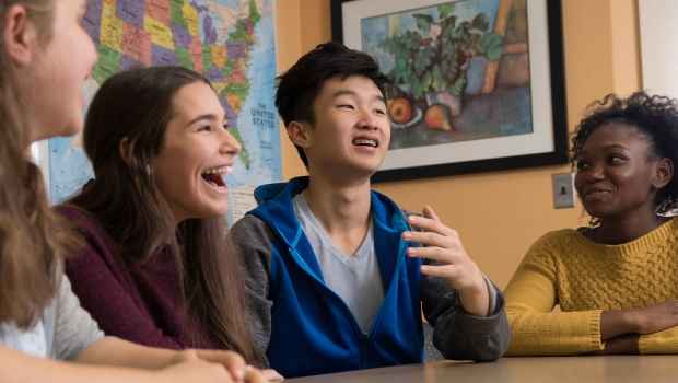 Group of adolescents laughing together at a table