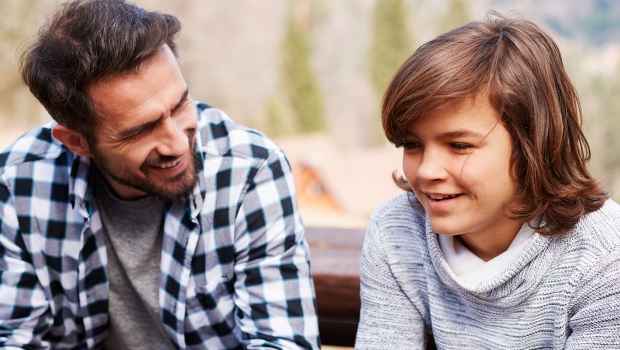 Parent and teen sit and talk on a bench