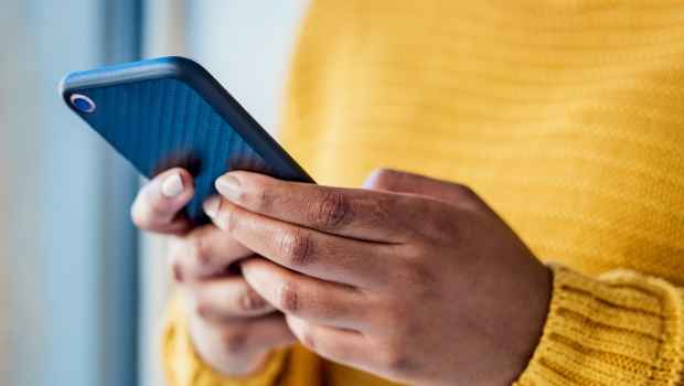 Hands holding smartphone, person wears bright yellow sweater
