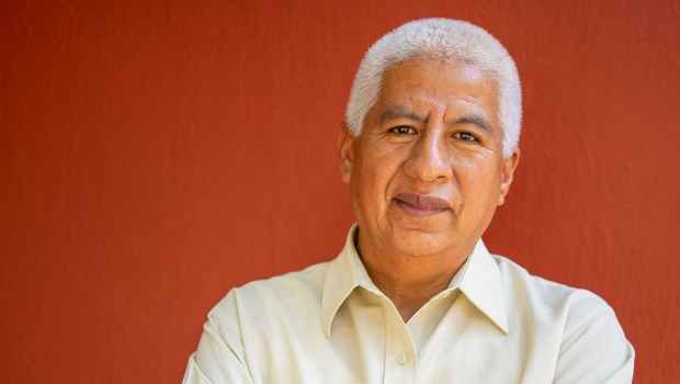 Stock image of an older adult in white button down in front of red wall
