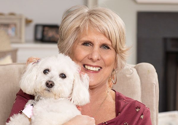 Woman smiling holding her white dog.