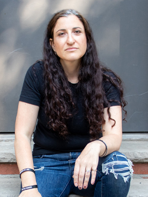 woman with long dark hair and black t-shirt staring at camera