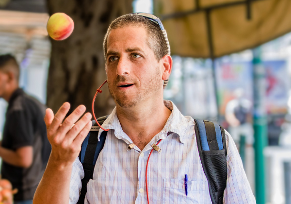 Man tossing a peach at an outdoor market