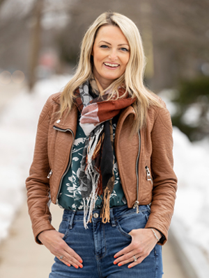 blonde woman outside with scarf and brown jacket