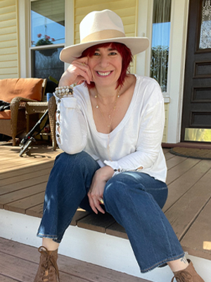 Woman on porch smiling in hat