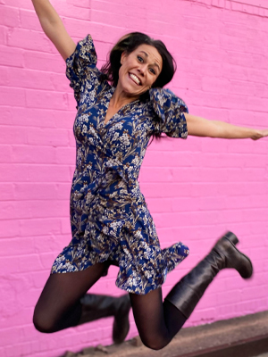 Woman jumping in air in front of pink wall