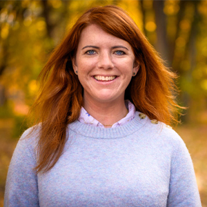 Woman smiling in front of fall background