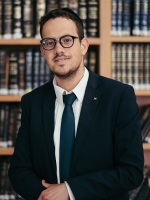 Man with glasses posing in front of book shelves