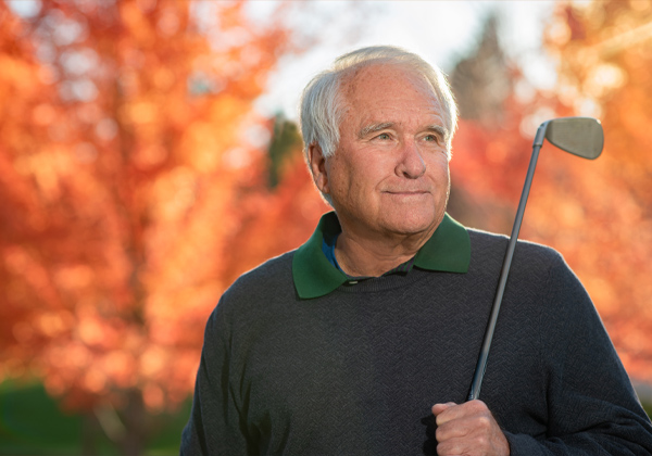 elderly gentleman with golf club looking into the distance
