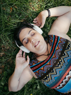 woman laying on grass with headphones on