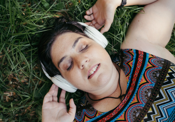 woman laying on grass with headphones on