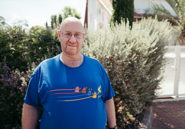 Man with glasses standing in front of bushes