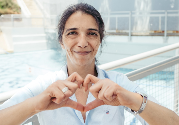 Woman smiling at camera and making a heart with her fingers