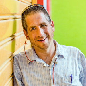 Man leaning against a wall and smiling with colorful background