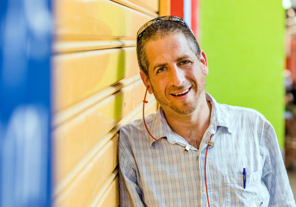 Man leaning against a wall and smiling with colorful background