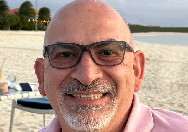 man with glasses and pink shirt smiling at camera