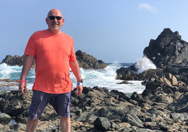 man in standing on rocks in front of the ocean