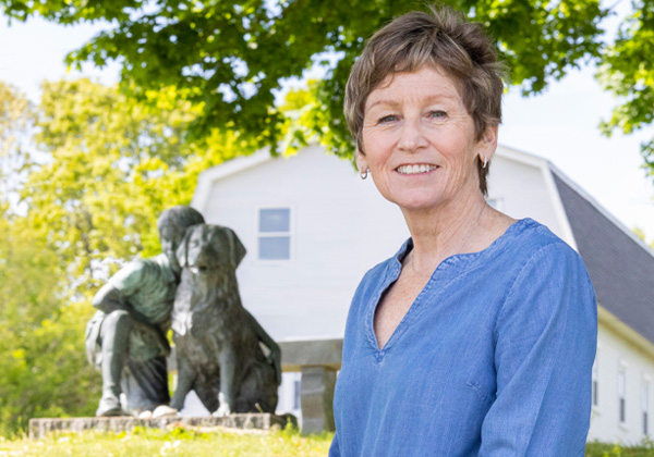 woman in blue shirt sitting outside and in front of a statue
