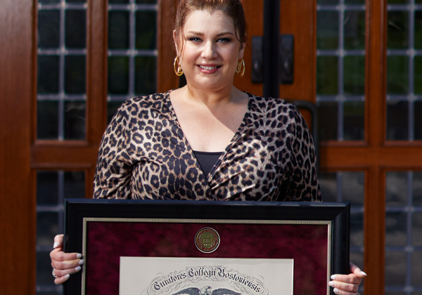 Woman holding up a framed degree