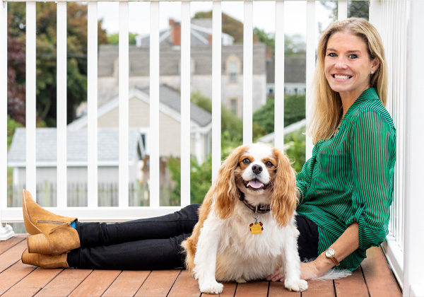 Woman sittng and smiling with her dog on a porch