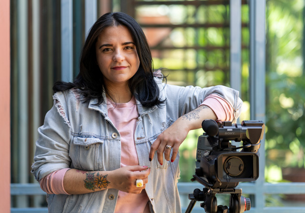 Woman wearing a jean jacket and leaning on a video camera