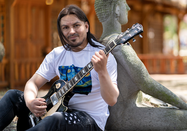 man with long hair playing guitar