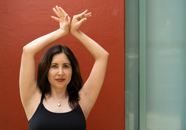 woman with arms raised against red background