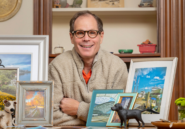 man with glasses smiling with photo frames in front of him